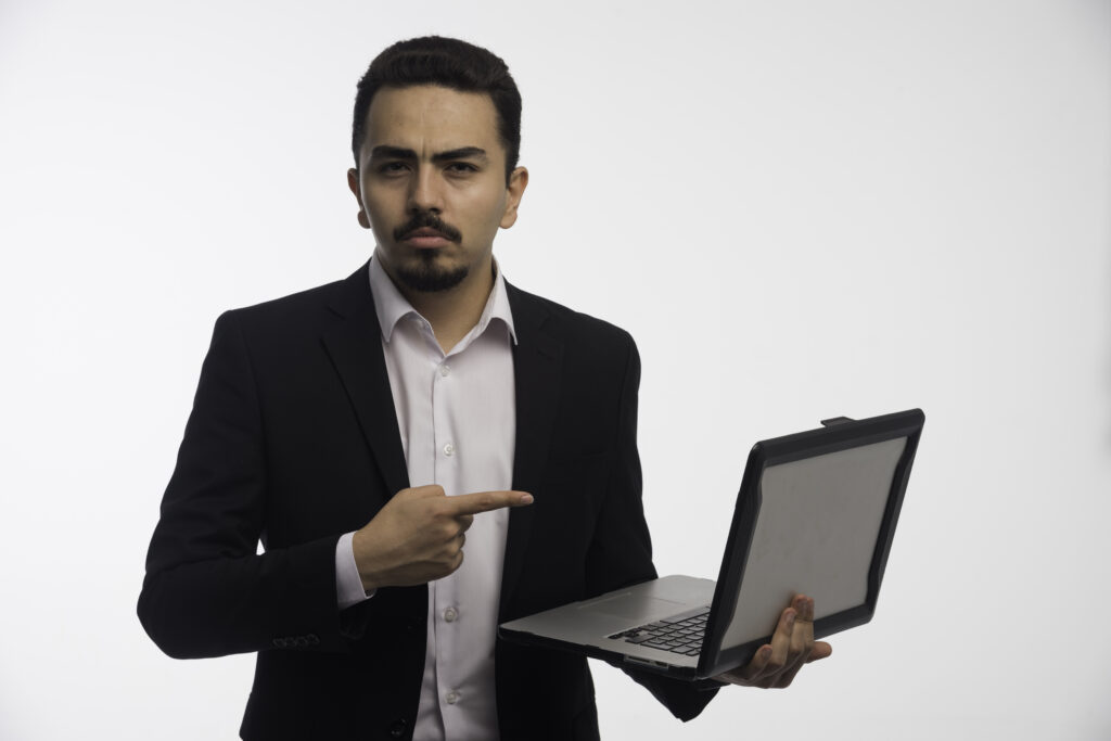 a businessman in dress code holding a laptop and pointing at it